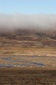 Mist rolls down the hillside in the Dombrava River Valley during autumn. Scoresbysund Fiord. East Greenland. 2005