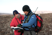 Tour guide Nette consults a field guide to show the flowers on now autumnal plants. Scoresbysund. East Greenland. 2005