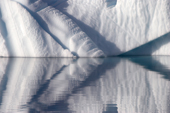 Sculptural shapes of an iceberg, enhanced by the mirror reflection. East Greenland. 2005