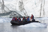 Ice cliffs of the Eielson Glacier tower over a tourist zodiac. Rypefjord. East Greenland. 2005