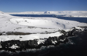 Snow covered crater, with basalt columns in foreground. Antarctica.