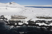 Snow filled crater and penguin colony, with basalt columns in foreground. Antarctica.