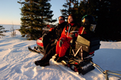 Couple on their snowmobile watch the sunset over sea ice near Lulea. Sweden. 2003