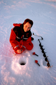 Woman Ice fishing on the sea ice off the coast of an island by Lulea. Sweden. 2003
