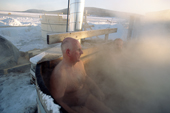 Tourist enjoys a steaming hot tub after a sauna and icy dip at the Ice Hotel. Jukkasjarvi. Sweden. 2003