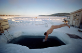 Tourist takes a cold dip in the River Torne after a sauna. Ice Hotel. Jukkasjarvi. Sweden. 2003