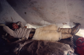 Inuit hunter in polar bear pants & seal skin Kamik rests in tent, whilst on a hunting trip. N.W.Greenland. 1980