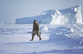 Inuit hunter, on sea ice, carrying a gun and harpoon while walrus hunting. Northwest Greenland. 1980