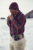 Inuit hunter, Qaavigannguaq, trimming his whip with a pocket knife while out hunting in the Spring near Moriussaq. Northwest Greenland. (1980)