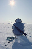 Inuit hunter, Ituko, rests on a piece of ice while out hunting walrus at their breathing holes in new ice during the Spring near Moriussaq, Northwest Greenland. (1980)