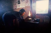 Inuit woman, Saufak Kivioq, lighting a Primus stove in her family's hut at the hunting camp at Narssarssuk. Bylot Sound, Northwest Greenland. (1980)