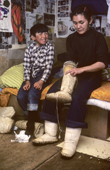 Saufak Kiviok, Inuit woman, and son in a hunter's hut. They wear sealskin kamik (boots). Thule, Northwest Greenland. 1980