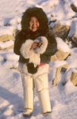 An Inuit girl, Sofie Jensen, warmly dressed in a fox fur hooded jacket (kapataq) and long sealskin kamik (boots). Thule, N.W. Greenland. 1987