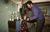 Inuit hunter, Ituko, cuts up walrus meat to feed to his huskies. Moriussaq, Northwest Greenland. (1987)