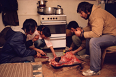 Inuit sharing a meal of muktuk (whale skin) & raw meat by a new cooker. Moriussaq, N.W.Greenland. 1987
