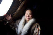 Raisa Serotetto, a Nenets woman, stands by the window inside her family's reindeer skin tent. Yamal, NW Siberia, Russia