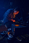 Light from the flames of a wood burning stove reflect off Raisa Serotetto, a Nenets woman, as she prepares to cook an evening meal inside her family's tent. Yamal, NW Siberia, Russia