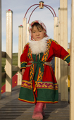 A Nenets girl dressed up in traditional dress for a holiday while playing in a children's playground. Gyda, Tazovsky Region, Yamal, Siberia, Russia