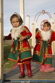 Two Nenets girls dressed up in traditional dress for a holiday while playing in a children's playground. Gyda, Tazovsky Region, Yamal, Siberia, Russia