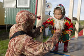 A Nenets father collects his daughter from a children's playground. Gyda, Tazovsky Region, Yamal, Siberia, Russia
