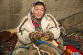Anastasia Yando, a 14 year old Nenets girl, sits in her family's tent while sewing a decorative panel, with a traditional design, onto felt that will be used to decorate a Nenets woman's summer coat. Gyda, Tazovsky region, Yamal, Siberia, Russia