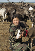Anastasia Yando, a Nenets girl, cuddles a young reindeer calf at her family's summer camp. Gyda, Tazovsky region, Yamal, Siberia, Russia