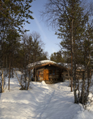 A log cabin at the Hotel Kakslauttanen, in snow covered woodland. Kakslauttanen, Lapland, Finland.