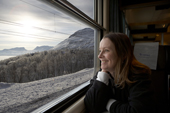A woman enjoys the winter scenery from the train. Kiruna to Narvik iron ore railway. Lapland, Sweden. MR